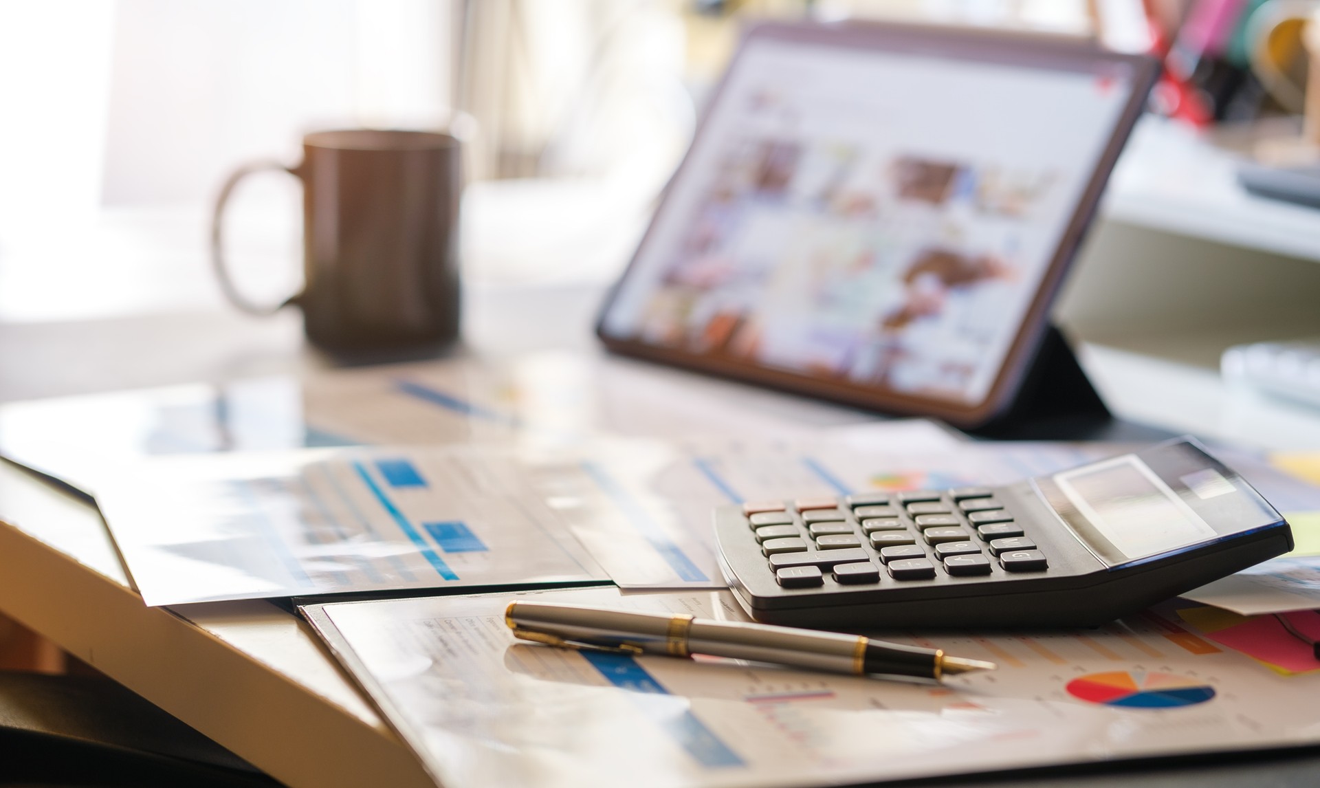 Business graphs, charts, digital tablet and calculator on office desk. Financial development, banking account and statistics.